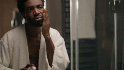 African American man in bathroom applying foamy gel shave beard face care bearded male smear foam beauty product prepare shaving looking at mirror reflection unshaven sad guy apple cream cosmetics - Powered by Adobe