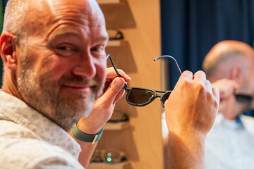 Happy man with bald head and sun glasses at shop 