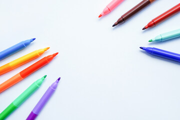 A collection of colorful felt-tip pens arranged in a circular pattern around a blank white center