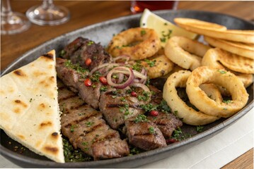 A platter of grilled meat with onion rings and flatbread