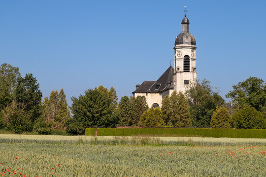 The Saint John the Evangelist Church of Park Abbey seen from a grain field with poppies in Heverlee, Leuven.