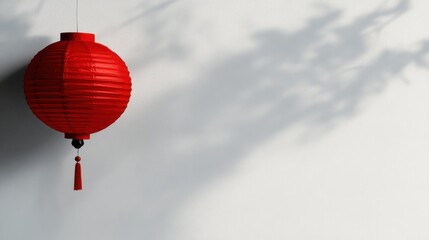 Obraz premium A vibrant red lantern hangs against a textured wall, its intricate design casting soft, artistic shadows during the evening. The tranquil atmosphere enhances the beauty of this decor
