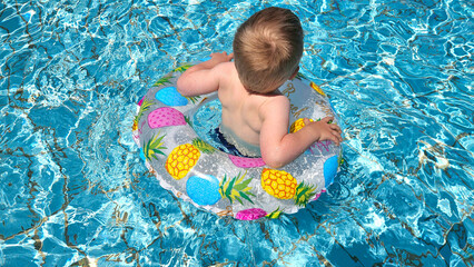 Little boy enjoys swimming in a pool with pineapple float. Summer vacation, happy childhood concept. High quality photo