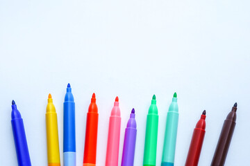 A row of colorful felt-tip markers is arranged in a semi-circle on a white background