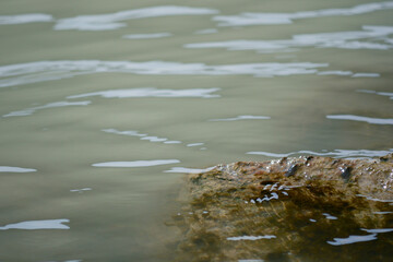 Water surface close up with a stone. Background abstracted wallpaper texture