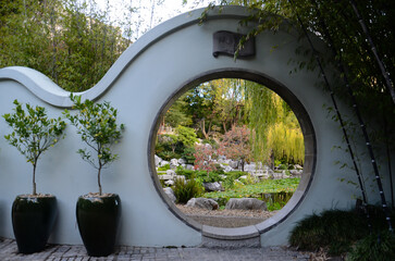 Serene garden view through a circular moon gate surrounded by lush greenery.