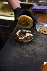 chef experto en hamburguesa enseñando el interior y los ingredientes de una hamburguesa rellena de...
