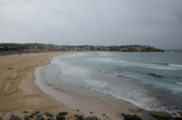 Overcast beach day with waves and cityscape in Sydney, Australia