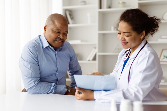 Happy African American doctor reviewing medical records with smiling black mature male patient during visit in modern clinic, therapist woman discussing test results with man, closeup