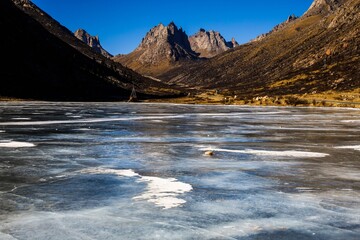 Frozen alpine lake at Nyenpo Yutse (Lianbao Yeze) Geological Park in Amdo, Tibet, surrounded by dramatic peaks and remote wilderness in the Greater Tibet region.