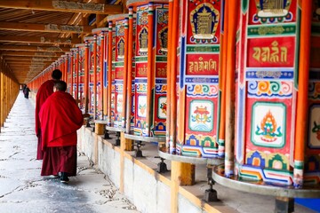 Tibetan monks turning vibrant prayer wheels at Labrang Monastery during Butter Lamp Festival, the...
