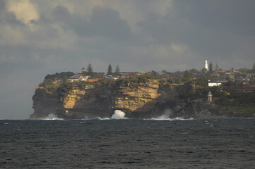 Dramatic cliffs and coastal homes under a moody sky in Sydney, Australia.