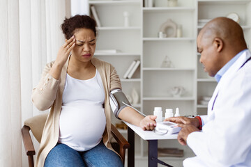 Gestational Hypertension. Black Doctor Measuring Arterial Blood Pressure Of Sick Pregnant Woman,...