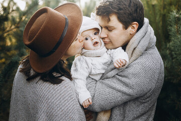 Happy family hugging and kissing with cute baby son in autumn woods in soft evening light....