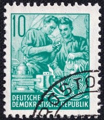 Workers fitters exchange experience on a 1953 GDR vintage postage stamp. Five-year Plan Series