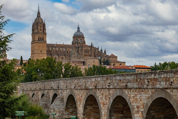Fototapeta premium View of the Roman Bridge and New Cathedral of Salamanca, Spain, with dramatic clouds over the historic skyline
