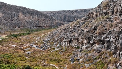volcanic arid landscapes with trils, cliffs, and scattedred vegetation.