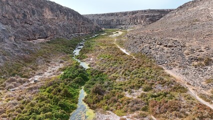 volcanic arid landscapes with trils, cliffs, and scattedred vegetation.