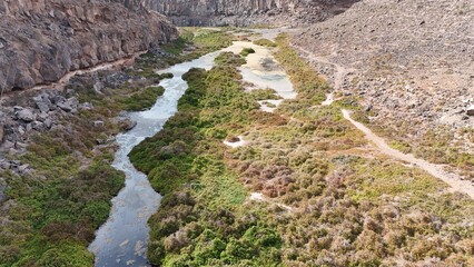 volcanic arid landscapes with trils, cliffs, and scattedred vegetation.