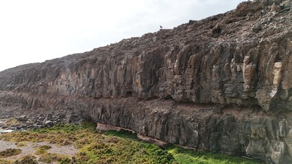 volcanic arid landscapes with trils, cliffs, and scattedred vegetation.
