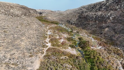 volcanic arid landscapes with trils, cliffs, and scattedred vegetation.