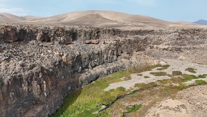 volcanic arid landscapes with trils, cliffs, and scattedred vegetation.