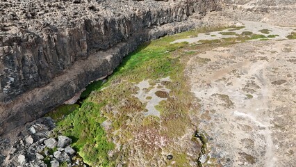 volcanic arid landscapes with trils, cliffs, and scattedred vegetation.
