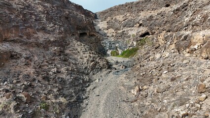 volcanic arid landscapes with trils, cliffs, and scattedred vegetation.