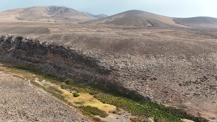 volcanic arid landscapes with trils, cliffs, and scattedred vegetation.
