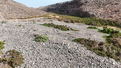 volcanic arid landscapes with trils, cliffs, and scattedred vegetation.