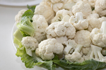 Fresh and raw cauliflower on the white plate.  The cauliflower  -  vegetable is cut into pieces on...
