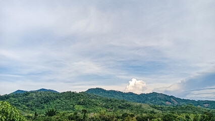 A beautiful landscape showcasing a lush tropical mountain range covered in dense forest beneath a...
