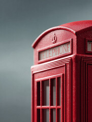 Obraz premium Closeup detail of a red telephone booth against a neutral background. Evokes nostalgia, communication, and travel themes. Suitable for editorial and design.