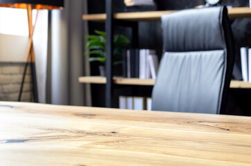 Modern business office with leather chair and wooden desk in front of elegant bookshelf with decor and books. Workspace interior for executive or entrepreneur