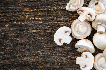Top view of fresh white mushrooms sliced and whole on rustic dark wooden background with copy space. Organic vegetarian food and cooking ingredient concept