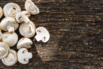 Top view of fresh white mushrooms sliced and whole on rustic dark wooden background with copy space. Organic vegetarian food and cooking ingredient concept