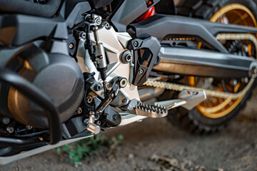 Close-up view of motorcycle engine and footpeg showcasing mechanical detail in an outdoor setting during daylight
