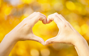 Hands in heart shape framing on nature background