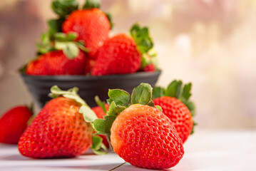 Pot with strawberries, a beautiful little black pot full of delicious strawberries on rustic wood, selective focus.