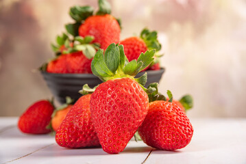 Pot with strawberries, a beautiful little black pot full of delicious strawberries on rustic wood, selective focus.