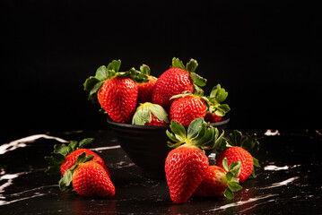 Jar with strawberries, a beautiful black jar full of delicious strawberries on a dark surface, black background, selective focus.