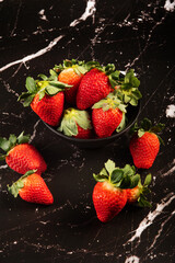 Jar with strawberries, a beautiful black jar full of delicious strawberries on a dark surface, black background, selective focus.