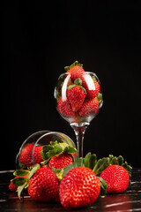 Bowls with strawberries, beautiful crystal bowls full of delicious strawberries on dark surface, black background, selective focus.