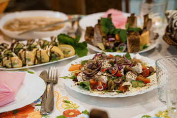 Lavish Mediterranean Feast on Table with Colorful Salads, Appetizers, and Drinks at Family Gathering in Warm Interior Setting.