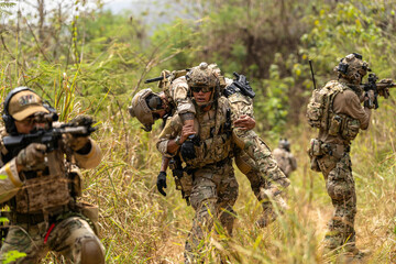 Fototapeta premium Soldier Carrying Injured Comrade During Tactical Combat Mission – Military Rescue Operation in Jungle, Armed Forces in Full Gear Providing Assistance Under Fire, Real Battlefield Scene