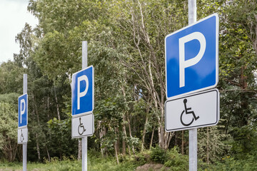 Accessible parking signs in a row indicating reserved parking spaces for people with disabilities near a public area