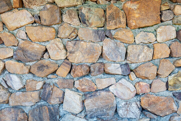 Rough stone wall made of irregular natural rocks used for rustic construction and garden landscaping