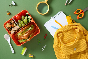 Flat lay of a student's daily items, including a nutritious bento lunch, stationery, and a yellow corduroy backpack