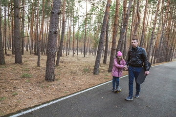 Fototapeta premium Father and daughter riding skateboards in the forest.