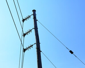 Wooden pole with electricity distribution. Green energy. Blue sky and summer day.